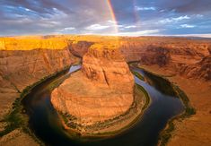 a rainbow shines in the sky over a river