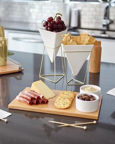 cheese, crackers and grapes are arranged on a table