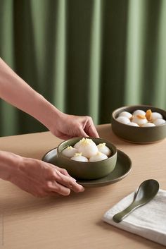 a person reaching for an egg in a bowl on a table next to another plate