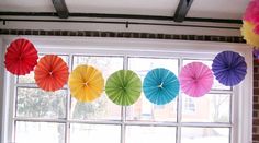 colorful paper umbrellas hanging in front of a window