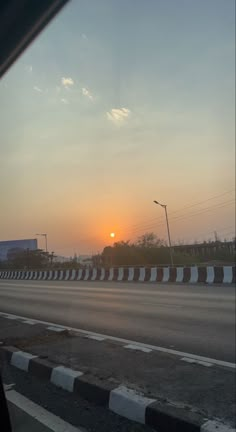 the sun is setting over an empty road