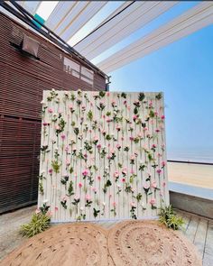 an outdoor area with flowers on the wall and two round rugs next to it