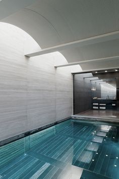 an indoor swimming pool with blue water and tiled flooring in a modern home setting