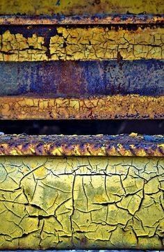 an old rusty bench is painted yellow and blue