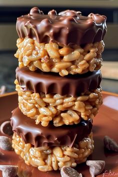 three chocolate covered cookies stacked on top of each other with nuts scattered around the edges