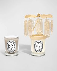 two candles sitting next to each other in front of a white background, one with a golden cage on it