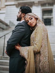 a man and woman standing next to each other in front of a building with stairs