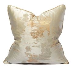 a gold and white pillow on a white background