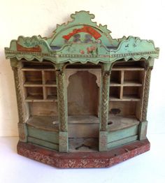 an old wooden toy house with shelves and cupboards on the top shelf, painted green