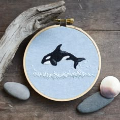 an orca whale in the water on a blue background with rocks and driftwood