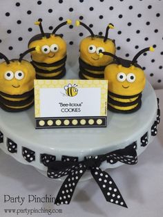 there are some yellow and black bees on the cake plate with a name tag that says beelicious cookies