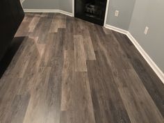 an empty room with gray walls and wood flooring in the corner is seen here