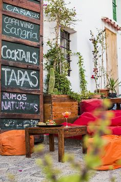 an outdoor seating area with red and orange cushions on the ground next to a sign that says cocktails taras