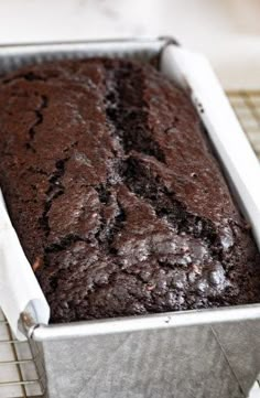 a loaf of chocolate cake sitting on top of a cooling rack