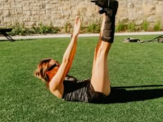 a woman laying on the ground with her feet up in the air while doing exercises