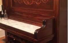 an old piano is sitting on the floor in front of a mirror and wine rack