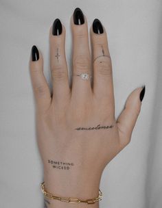 a woman's hand with black nail polish and cross tattoo on her left wrist