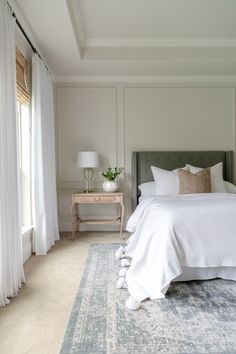 a large white bed sitting in a bedroom on top of a blue and white rug