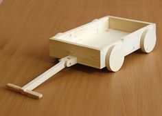 a wooden toy car with wheels on a wood table top, ready to be assembled