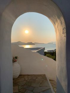 the sun is setting through an arched doorway