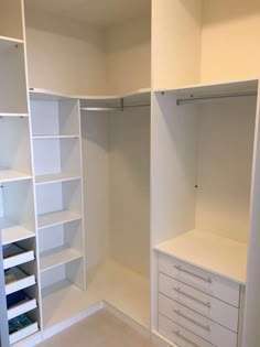 an empty closet with white shelves and drawers