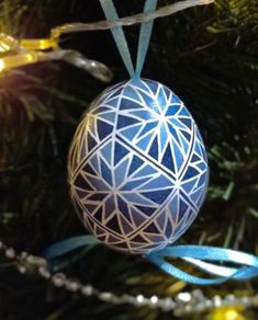 an ornament hanging from the top of a christmas tree with blue ribbons on it