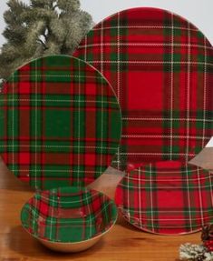 a plaid plate and bowl on a wooden table with pine branches in the background,