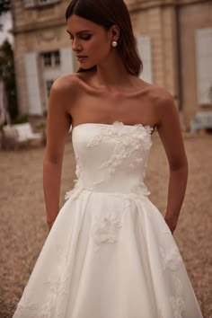 a woman in a white dress is standing outside