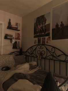 an unmade bed with pictures on the wall above it and other things in the background