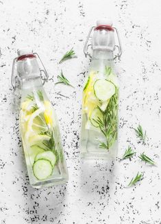 two bottles filled with cucumbers and lemon slices