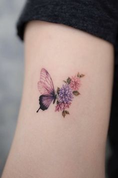 a small butterfly with pink flowers on the side of her leg and it's wings spread