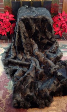 an animal fur rug on the floor in front of a fireplace with poinsettis