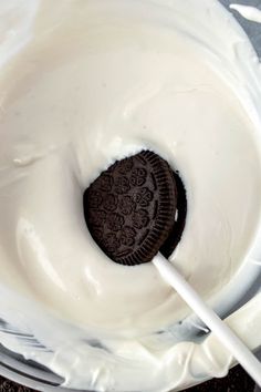 an oreo cookie in a glass bowl with white frosting and a straw sticking out of it