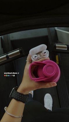 a hand holding a pink object with eyes on it's face in the back seat of a car