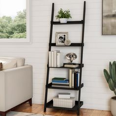 a living room with a white couch and black ladder bookshelf