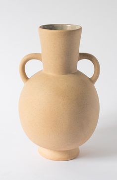 a white vase sitting on top of a table next to a white wall and floor