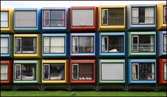 a multicolored building with many windows and balconies on the sides, in front of a grassy area