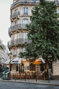 an old building with tables and chairs in front of it on the side of a street