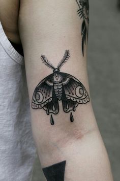 a black and white moth tattoo on the arm