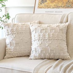 two pillows sitting on top of a couch next to a plant