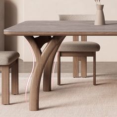 a wooden table with two chairs and a vase on it's end, in front of a beige wall