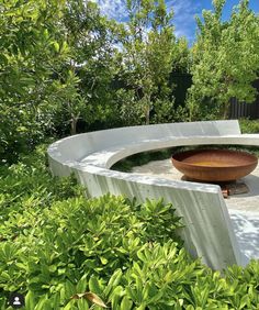 a bowl is sitting in the middle of a circular garden area with trees and bushes