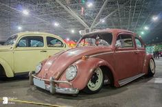 an old vw bug is on display in a showroom with other cars behind it