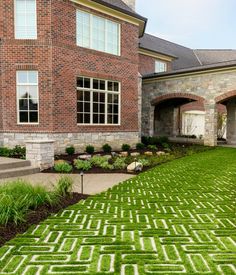 a large brick house with grass in the front yard and landscaping on either side of it