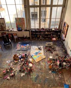 an artist's studio with lots of paint on the floor and various objects scattered about