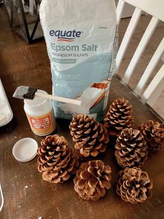 some pine cones sitting on top of a wooden table next to a bag of epsom salt