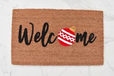 a welcome mat with a christmas ornament on it