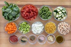 several bowls filled with different types of vegetables and seasonings on a wooden table top