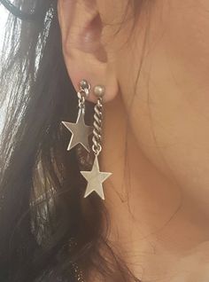 a close up of a person wearing earrings with stars hanging from the back of them