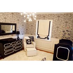 a living room with black and white furniture and wallpaper on the walls, including a chandelier